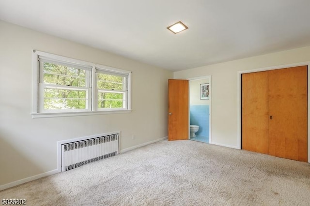 unfurnished bedroom featuring connected bathroom, baseboards, carpet, and radiator