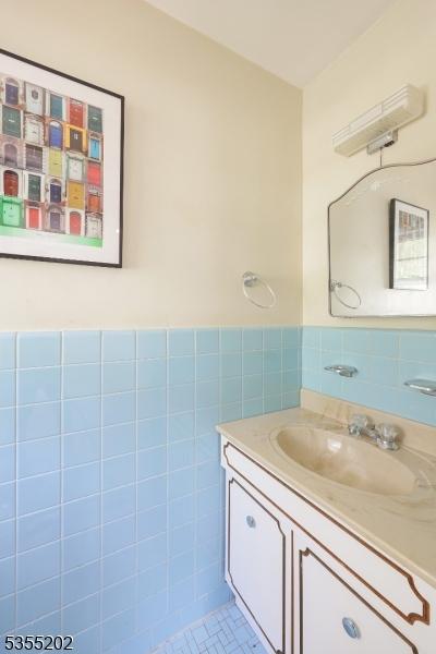 bathroom with wainscoting, tile walls, vanity, and tile patterned floors