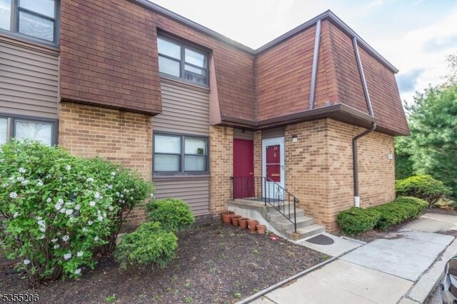 property entrance featuring brick siding and mansard roof