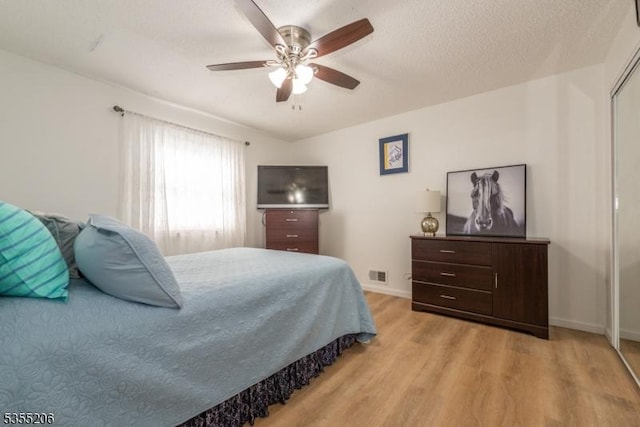 bedroom with baseboards, ceiling fan, wood finished floors, and visible vents