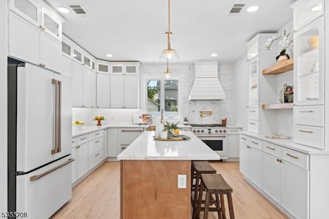kitchen with visible vents, high end appliances, premium range hood, and light wood-type flooring