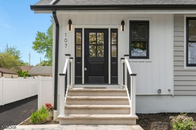 property entrance featuring roof with shingles, fence, and board and batten siding