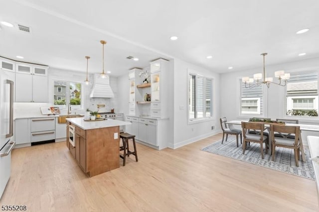 kitchen featuring a center island, light wood-style flooring, plenty of natural light, and custom exhaust hood