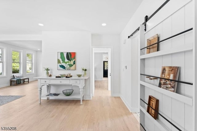 hall featuring recessed lighting, baseboards, a barn door, and light wood finished floors