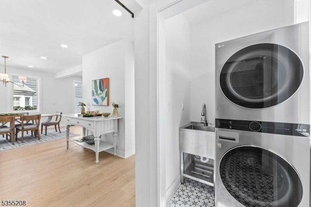 laundry room with laundry area, a notable chandelier, light wood-style floors, recessed lighting, and stacked washer and clothes dryer
