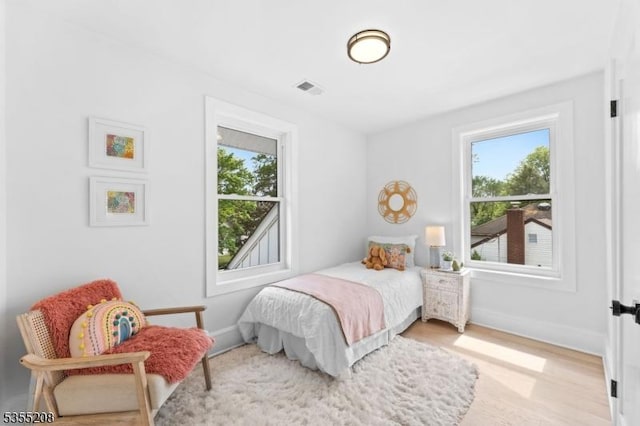 bedroom featuring baseboards, wood finished floors, and visible vents
