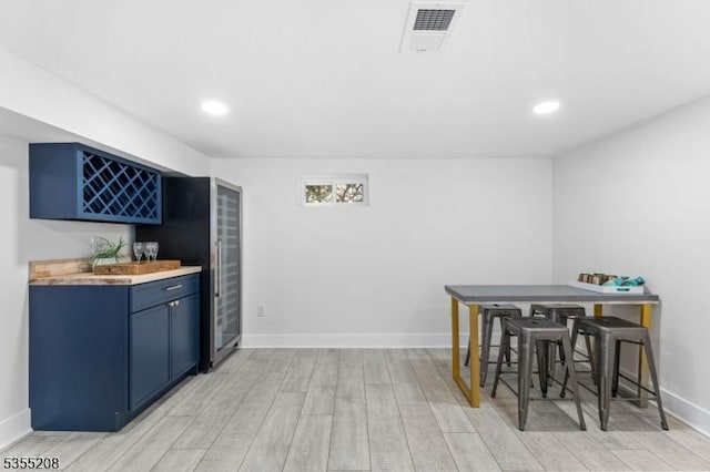 interior space featuring visible vents, baseboards, recessed lighting, light wood finished floors, and bar area