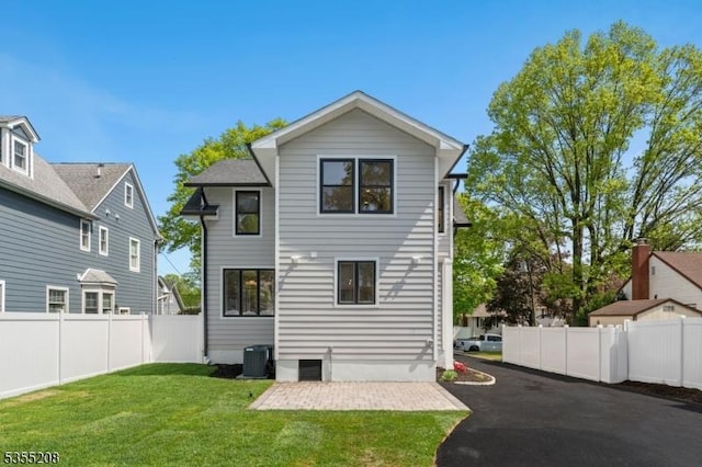 rear view of property featuring a lawn, a fenced backyard, central air condition unit, and a patio