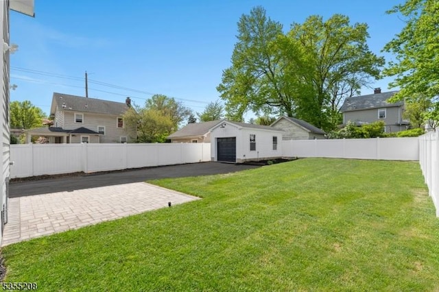 view of yard with a garage, an outdoor structure, a fenced backyard, and a patio area
