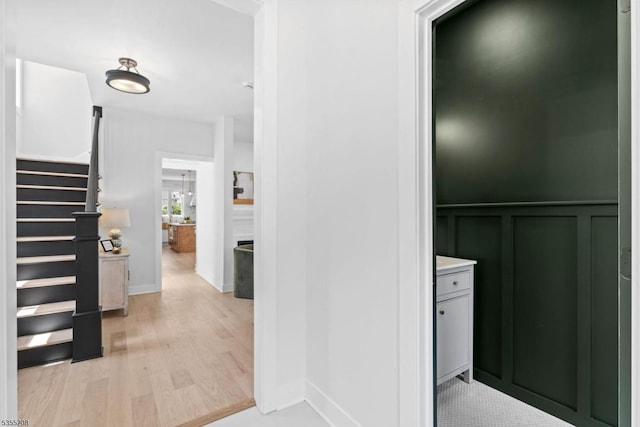 interior space featuring stairs, light wood-style flooring, and a decorative wall