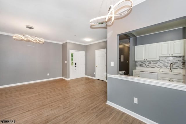 kitchen featuring a chandelier, a sink, ornamental molding, white cabinetry, and white dishwasher