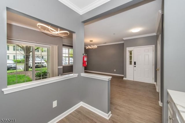entryway with ornamental molding, a chandelier, wood finished floors, and baseboards