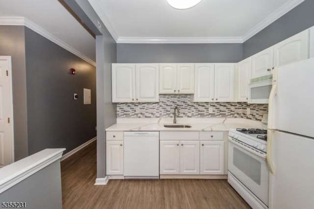 kitchen with white appliances, a sink, light wood finished floors, white cabinets, and crown molding
