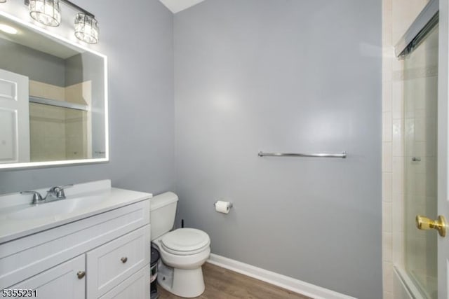 full bathroom with toilet, wood finished floors, vanity, and baseboards