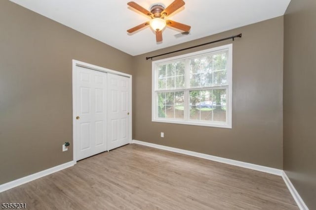 unfurnished bedroom with baseboards, light wood-style flooring, and a closet