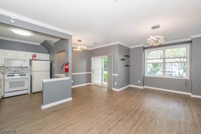 kitchen featuring a chandelier, white appliances, light countertops, white cabinets, and crown molding