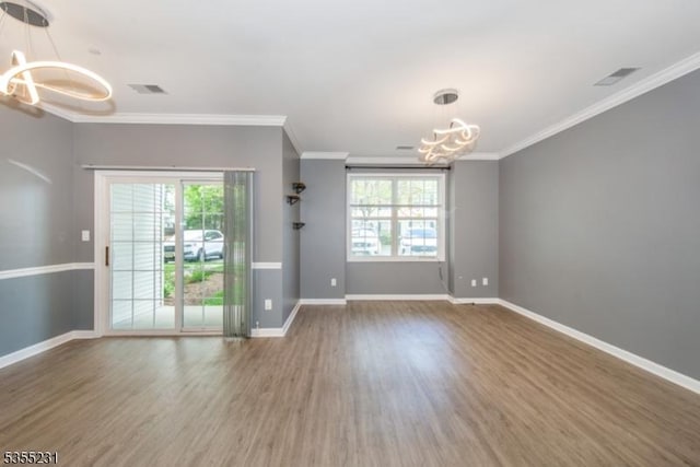 spare room featuring a chandelier, wood finished floors, ornamental molding, and baseboards