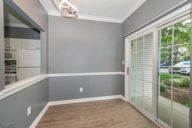 unfurnished room featuring crown molding, light wood-style floors, baseboards, and a chandelier