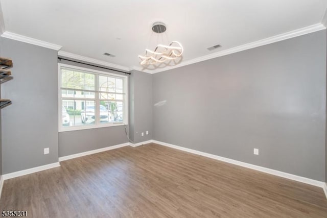 unfurnished room with a chandelier, crown molding, wood finished floors, and baseboards