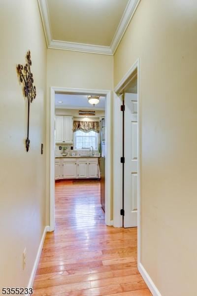 hallway with crown molding, a sink, light wood-style flooring, and baseboards