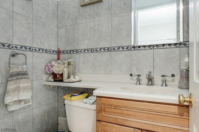 half bath featuring vanity, backsplash, toilet, and tile walls