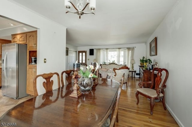 dining room with an inviting chandelier, ornamental molding, and light wood-style flooring
