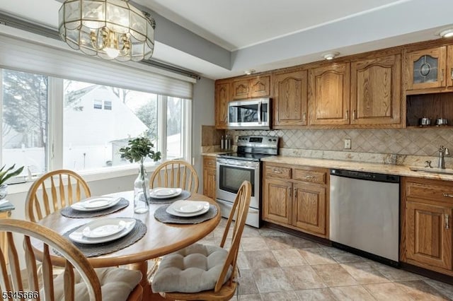 kitchen featuring a sink, appliances with stainless steel finishes, brown cabinetry, and backsplash