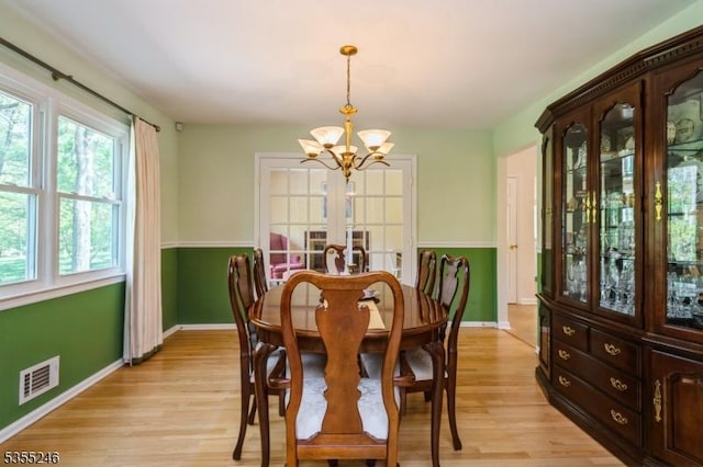 dining area featuring french doors, visible vents, baseboards, a chandelier, and light wood-style floors