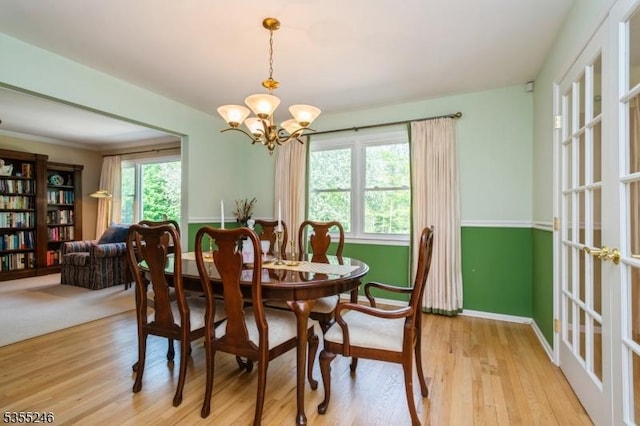 dining space with baseboards, an inviting chandelier, and light wood-type flooring