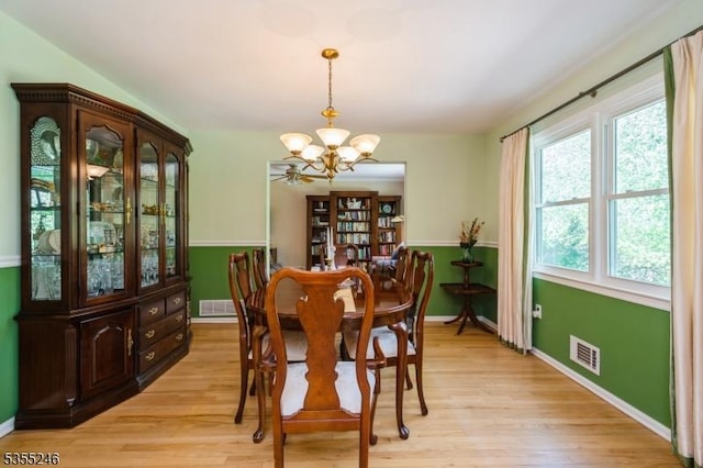 dining space with light wood-style floors, baseboards, a notable chandelier, and visible vents