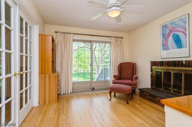 living area with ceiling fan, a fireplace, french doors, and hardwood / wood-style floors