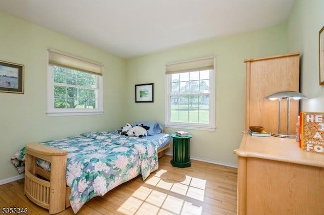 bedroom with baseboards, light wood finished floors, and multiple windows