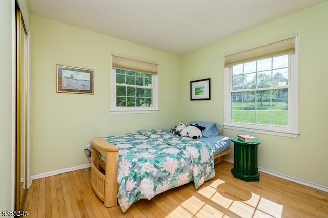bedroom with light wood-style floors, baseboards, and multiple windows