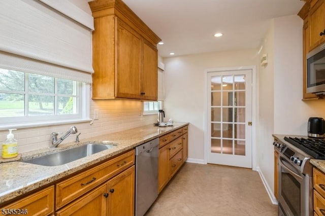 kitchen featuring brown cabinetry, a sink, decorative backsplash, and appliances with stainless steel finishes