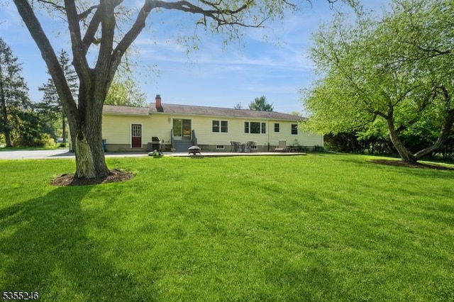 back of property featuring entry steps, a patio, and a yard