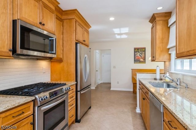 kitchen featuring a sink, baseboards, stainless steel appliances, and brown cabinets