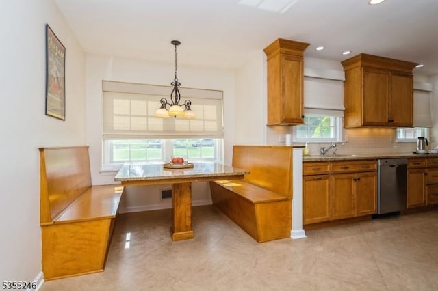 kitchen with decorative backsplash, stainless steel dishwasher, brown cabinetry, and breakfast area