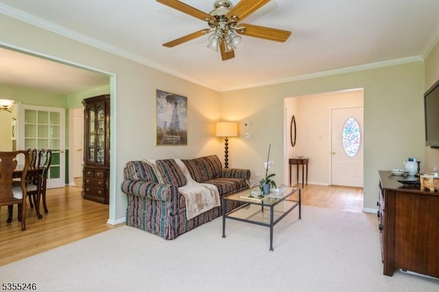 living room with crown molding, a ceiling fan, and light wood-style floors