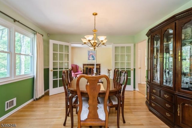 dining space with a notable chandelier, visible vents, baseboards, and light wood-type flooring