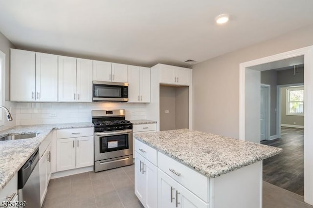 kitchen with a sink, white cabinets, backsplash, and stainless steel appliances