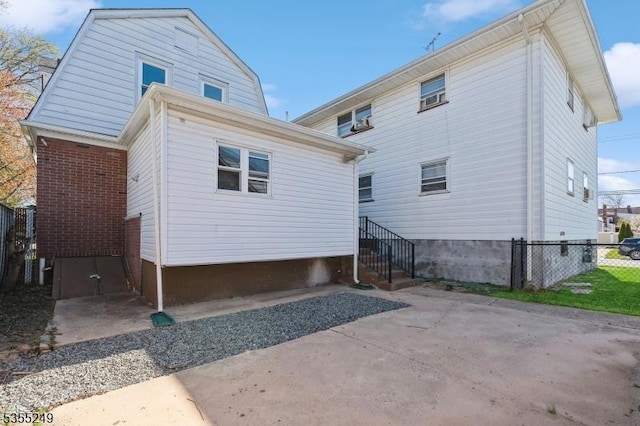 back of house featuring fence, a patio, and a gambrel roof
