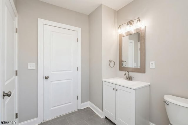 half bathroom with vanity, tile patterned floors, baseboards, and toilet