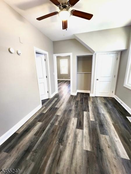 interior space with baseboards, ceiling fan, and dark wood-type flooring