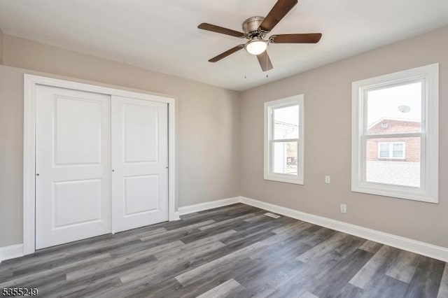 unfurnished bedroom featuring baseboards, dark wood-style floors, ceiling fan, and a closet