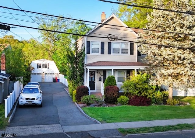 view of front of property featuring a detached garage, an outdoor structure, a front yard, and a chimney