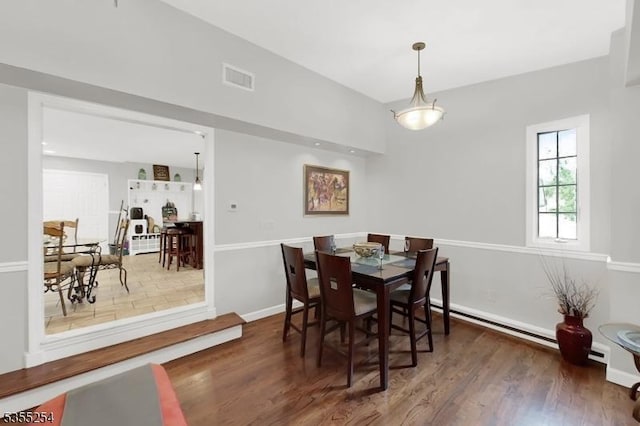 dining area with wood finished floors, a baseboard radiator, and baseboards