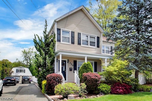 traditional-style home featuring an outbuilding and a porch