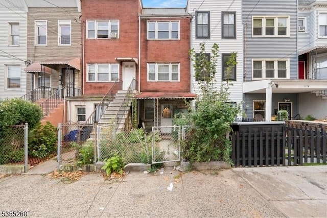 townhome / multi-family property featuring brick siding, a fenced front yard, and a gate