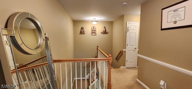 hall with baseboards, carpet flooring, and an upstairs landing