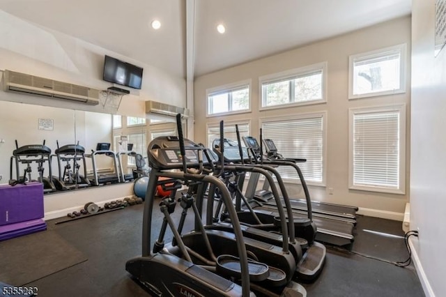 workout area featuring baseboards, recessed lighting, a towering ceiling, and a wall mounted AC